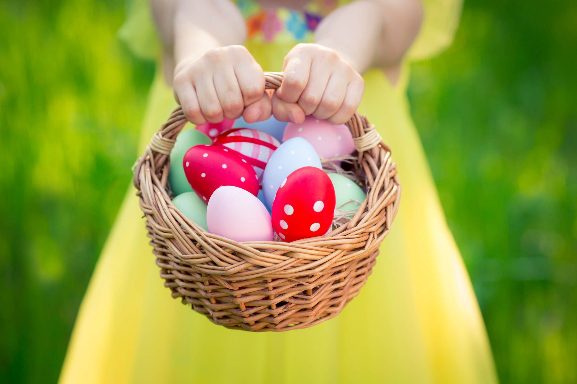Child holding basket with Easter eggs